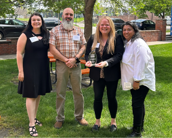 Arapahoe/Douglas Works! staff members standing outside, holding the 2025 Program Partner of the Year Silver Flame Award.