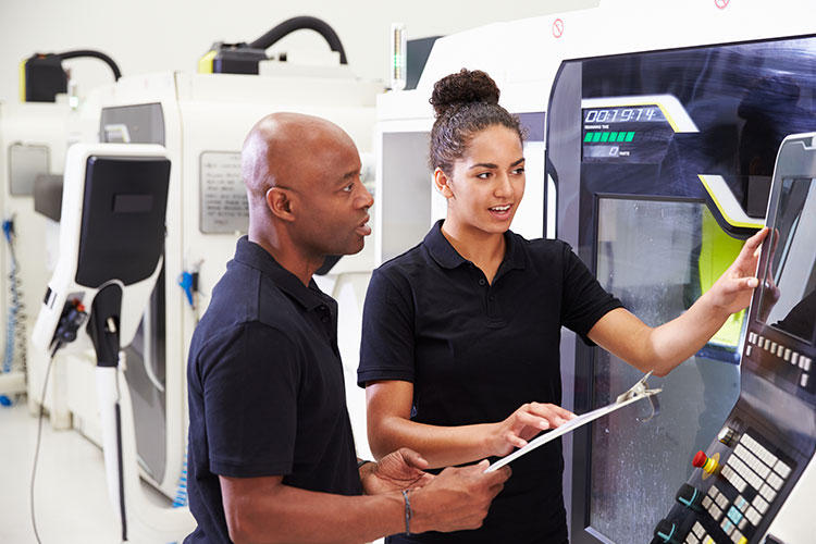 Apprenti féminin travaillant avec l'ingénieur sur les machines CNC